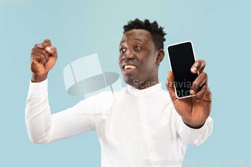 Image of Young african-american man isolated on blue studio background, human emotions concept.