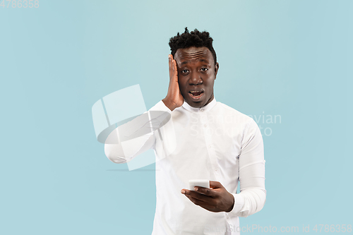 Image of Young african-american man isolated on blue studio background, human emotions concept.