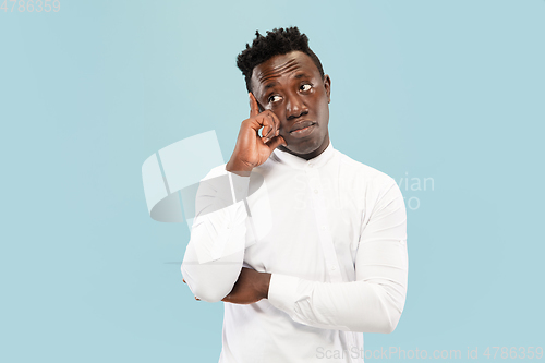 Image of Young african-american man isolated on blue studio background, human emotions concept.