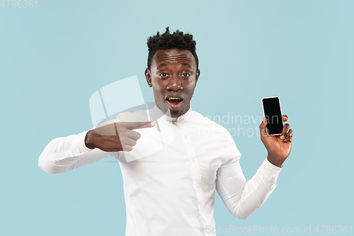 Image of Young african-american man isolated on blue studio background, human emotions concept.