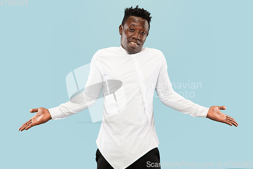 Image of Young african-american man isolated on blue studio background, human emotions concept.