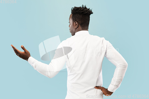 Image of Young african-american man isolated on blue studio background, human emotions concept.