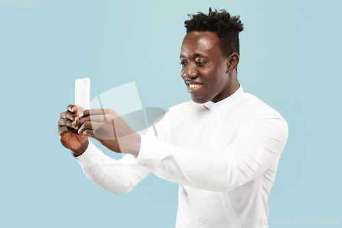 Image of Young african-american man isolated on blue studio background, human emotions concept.