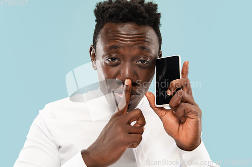 Image of Young african-american man isolated on blue studio background, human emotions concept.