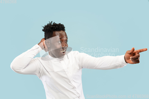 Image of Young african-american man isolated on blue studio background, human emotions concept.