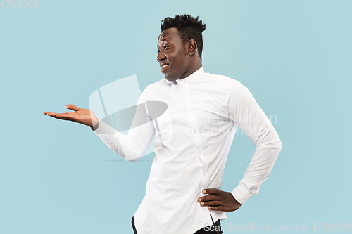 Image of Young african-american man isolated on blue studio background, human emotions concept.