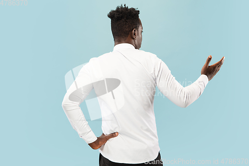 Image of Young african-american man isolated on blue studio background, human emotions concept.