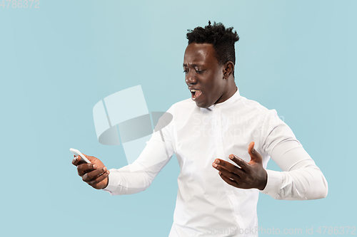 Image of Young african-american man isolated on blue studio background, human emotions concept.