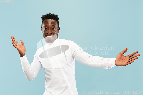 Image of Young african-american man isolated on blue studio background, human emotions concept.