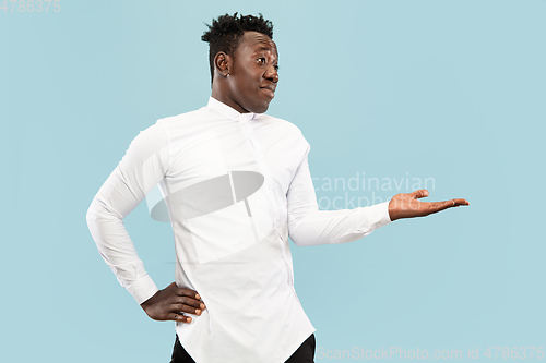 Image of Young african-american man isolated on blue studio background, human emotions concept.