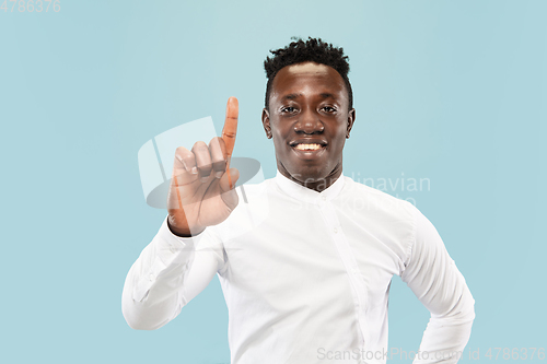 Image of Young african-american man isolated on blue studio background, human emotions concept.