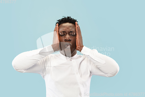 Image of Young african-american man isolated on blue studio background, human emotions concept.