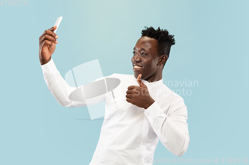 Image of Young african-american man isolated on blue studio background, human emotions concept.