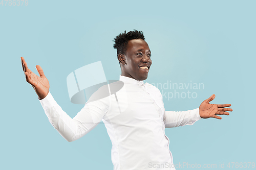 Image of Young african-american man isolated on blue studio background, human emotions concept.