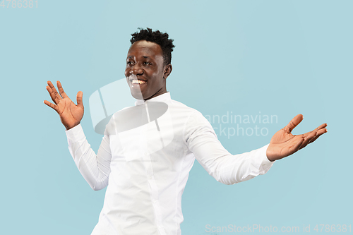 Image of Young african-american man isolated on blue studio background, human emotions concept.