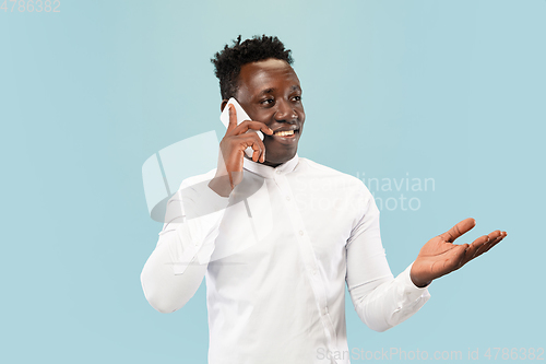 Image of Young african-american man isolated on blue studio background, human emotions concept.