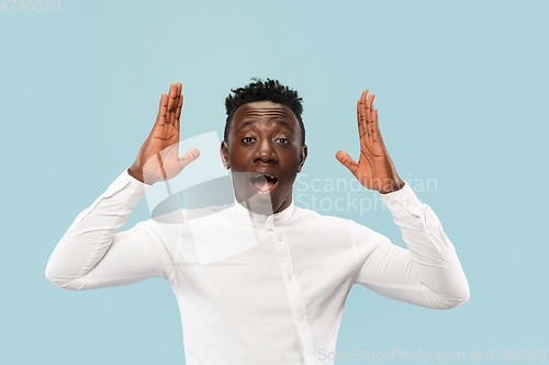 Image of Young african-american man isolated on blue studio background, human emotions concept.