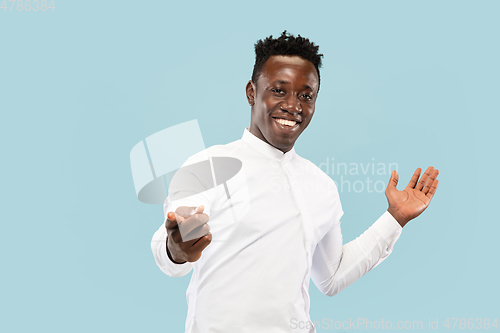 Image of Young african-american man isolated on blue studio background, human emotions concept.