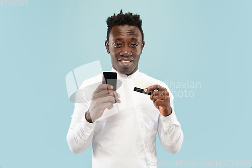 Image of Young african-american man isolated on blue studio background, human emotions concept.