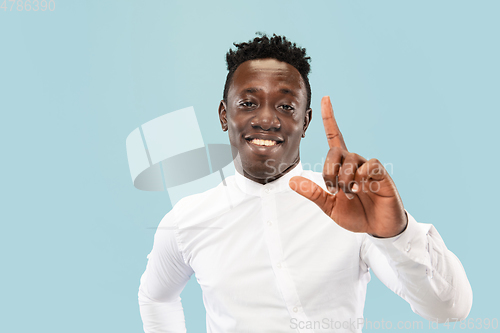 Image of Young african-american man isolated on blue studio background, human emotions concept.