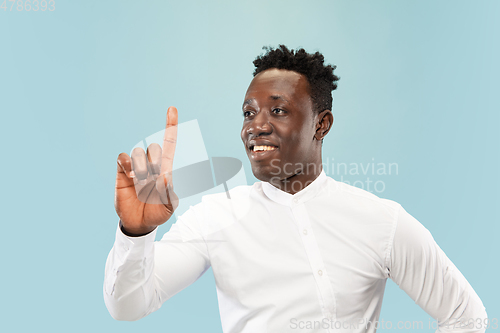 Image of Young african-american man isolated on blue studio background, human emotions concept.