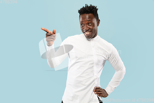 Image of Young african-american man isolated on blue studio background, human emotions concept.