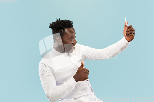 Image of Young african-american man isolated on blue studio background, human emotions concept.