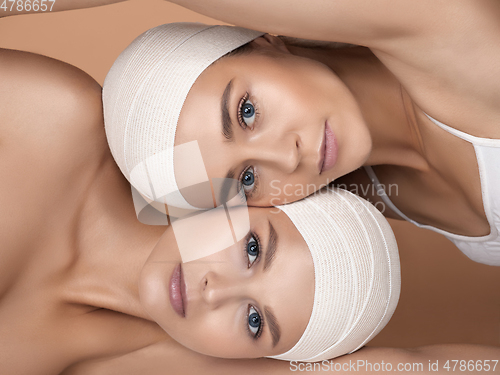 Image of Portrait of beautiful young women isolated on brown studio background