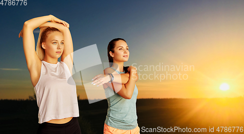 Image of women with fitness trackers stretching outdoors