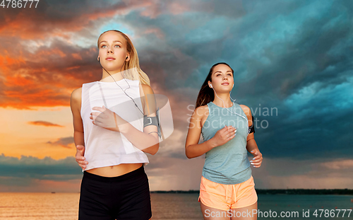 Image of young women with earphones and smartphones running