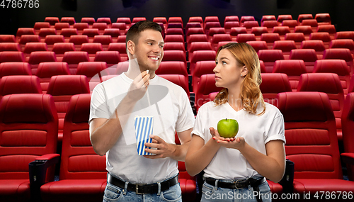 Image of couple with popcorn and apple at cinema