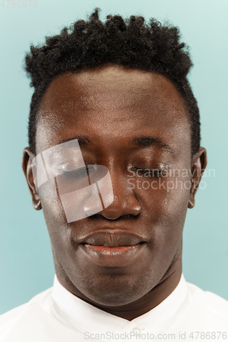 Image of African-american young man\'s close up portrait on blue background