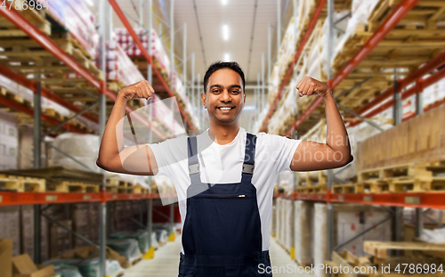 Image of happy indian worker showing his power at warehouse