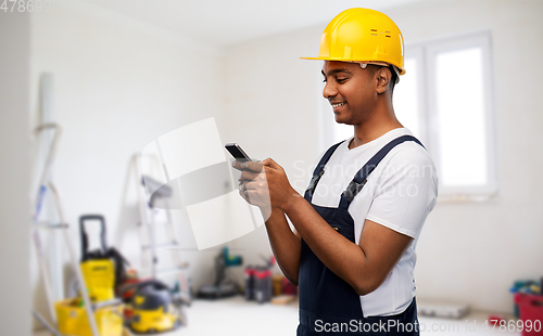 Image of happy indian or builder in helmet using smartphone