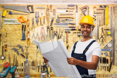 Image of happy indian builder in helmet with blueprint