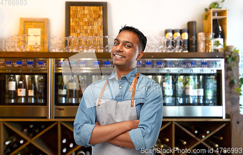 Image of smiling indian barman or waiter in apron at bar
