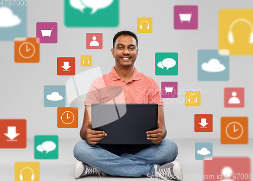 Image of happy indian man with laptop computer on floor