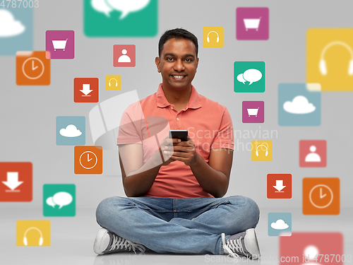 Image of happy indian man using smartphone over app icons