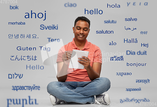 Image of indian man in polo shirt writing to notebook