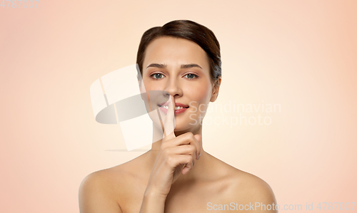 Image of beautiful young woman holding finger on lips