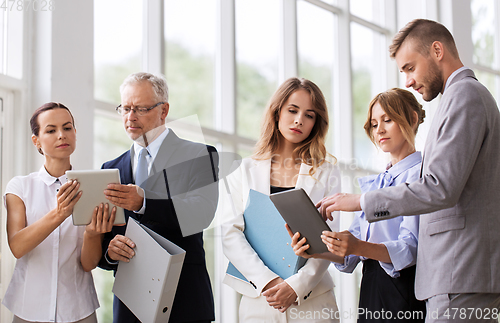 Image of business team with tablet pc and folders at office