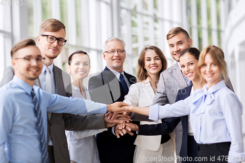 Image of happy business people stacking hands at office