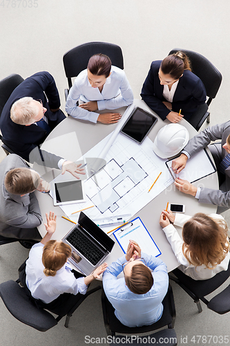 Image of architects with laptop and blueprint at office