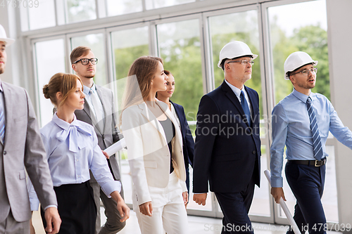 Image of business team in helmets walking along office