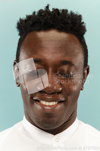 Image of African-american young man\'s close up portrait on blue background