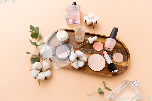 Image of makeup, perfume and cosmetics on wooden tray