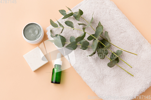 Image of serum, clay mask, oil and eucalyptus on bath towel