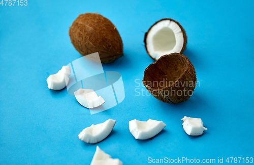 Image of whole and cracked coconut on blue background