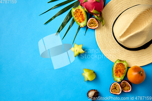 Image of straw hat and exotic fruits on blue background