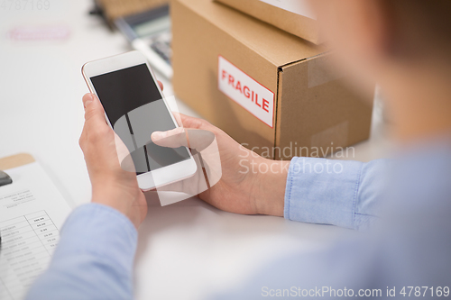 Image of hands with smartphone and parcels at post office